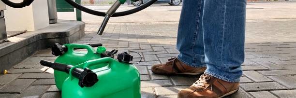 Man filling plastic fuel cans at a petrol station